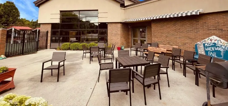 Patio tables beside a painted rock that reads Music speaks when words fail